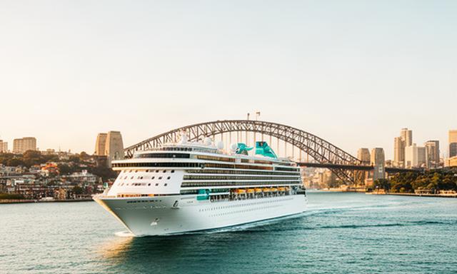Cruise ship leaving Sydney Harbour beneath the Harbour Bridge, with the city shoreline visible in the morning light